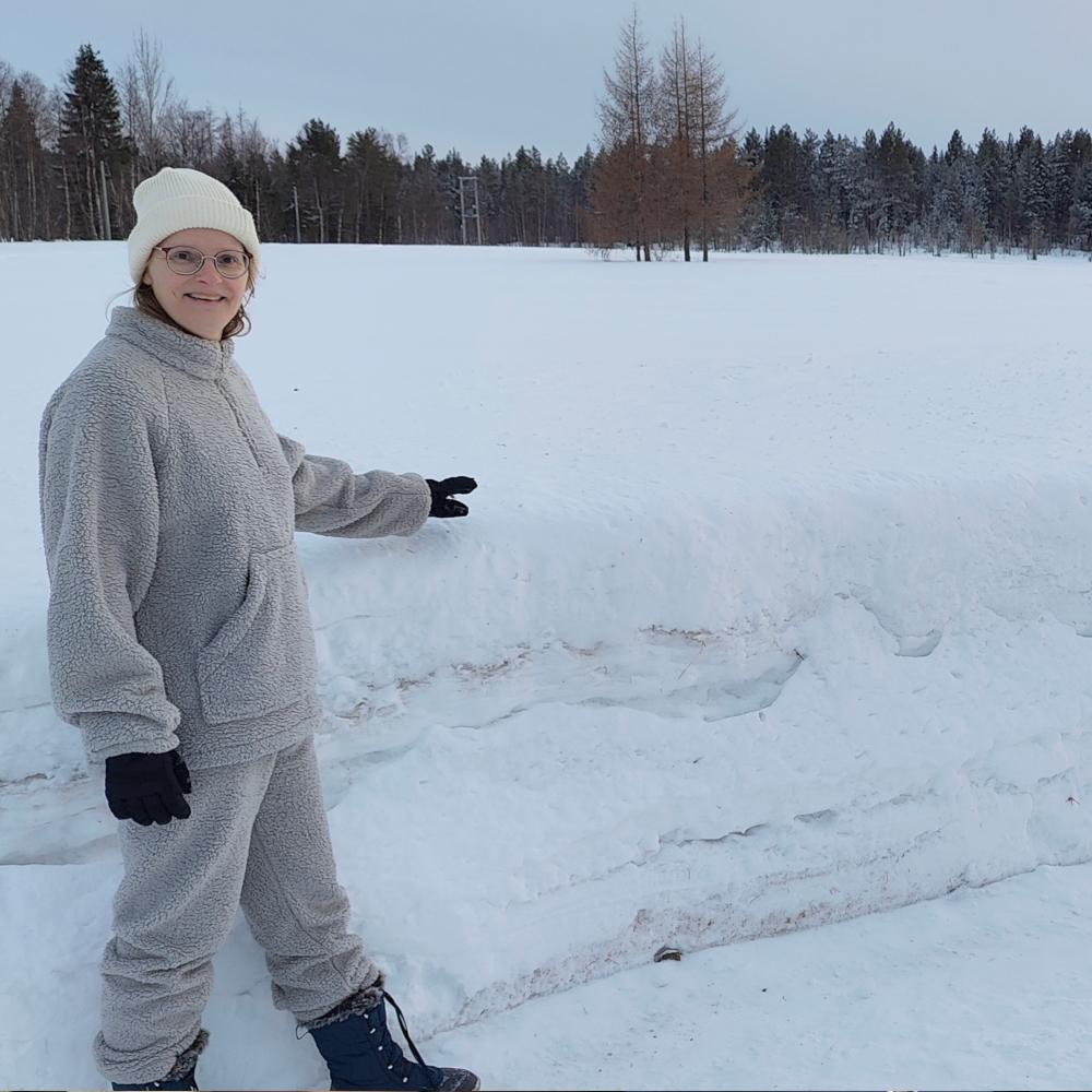 Els Bancken staat naast een borsthoge sneeuwbank in Tepasto, in Fins Lapland, waarmee ze de dikte van de wintersneeuw laat zien.