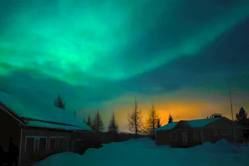 Een groene aurora die over de hemel boven de sneeuw trekt, met een oranje gloed aan de horizon door de lichtjes van het dorp die op de lage bewolking weerkaatsen, Fins Lapland. Aurealis Creatief.