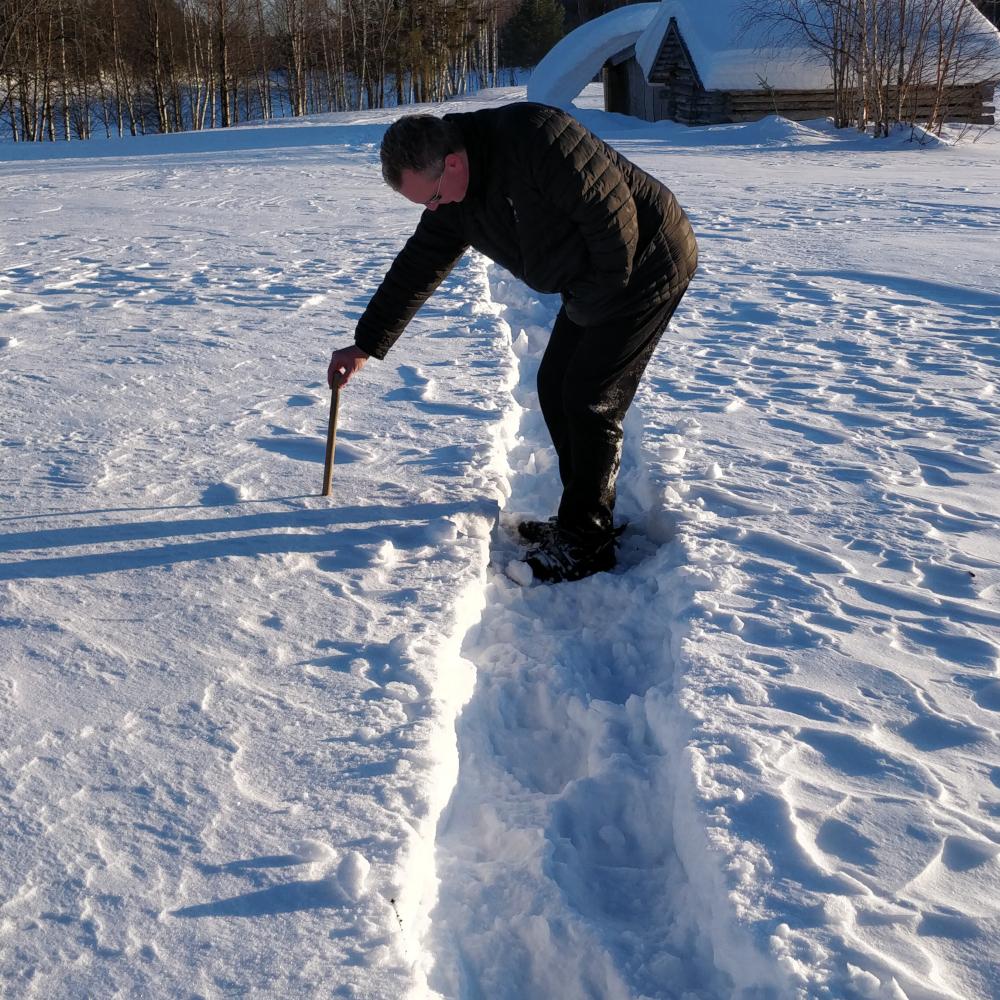 In Lapland meten hoe dik de sneeuwkorst is; het oppervlak is stevig genoeg om op te staan, maar op sommige plekken nog zacht.